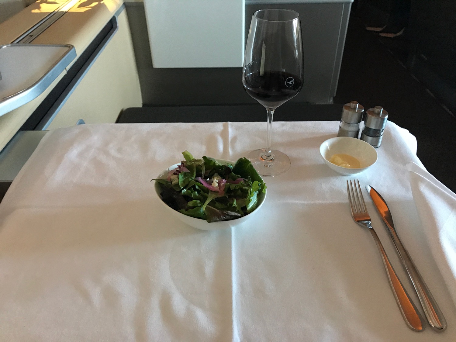 a salad bowl and a glass of wine on a table