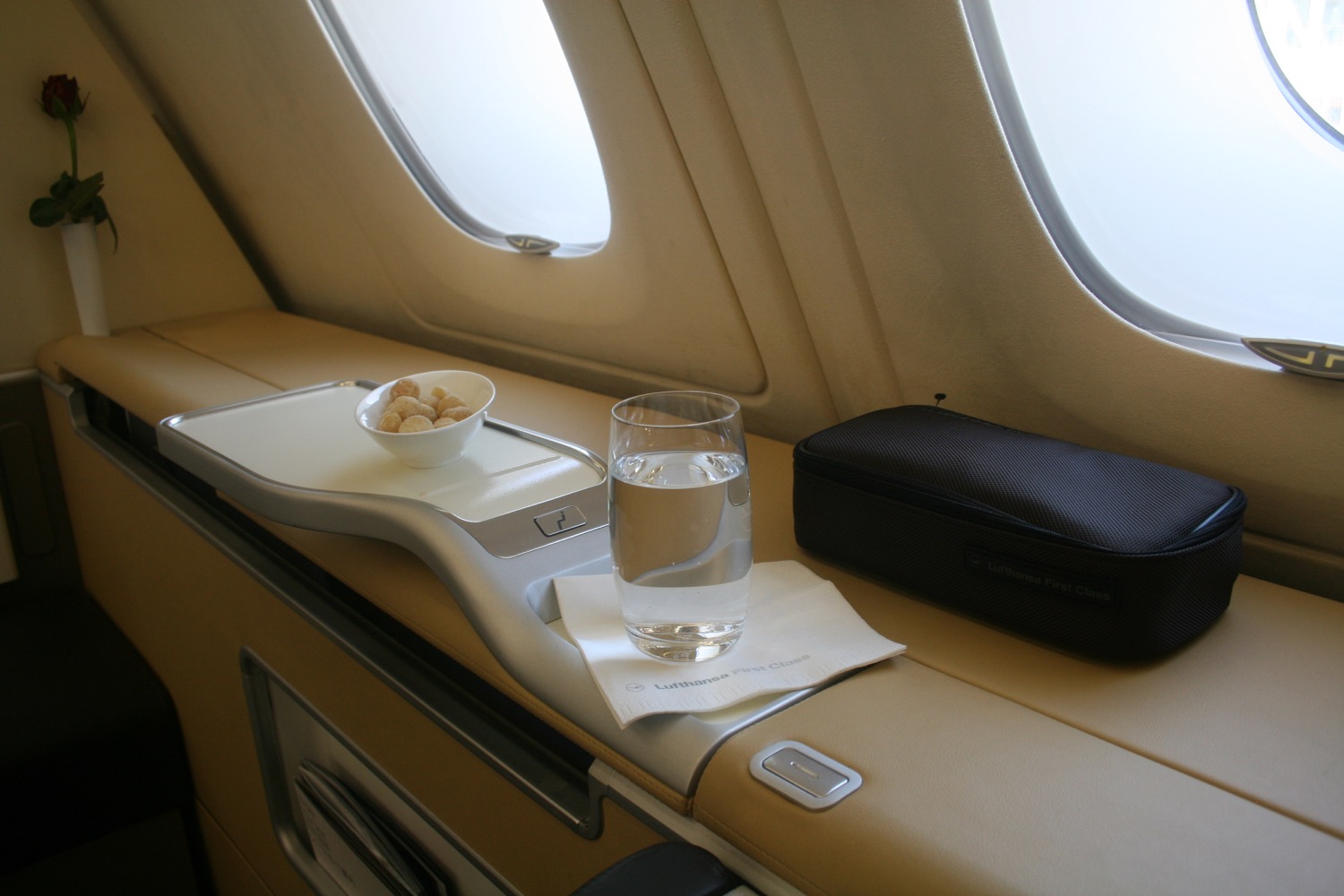 a glass of water and a bowl of food on a tray in a plane