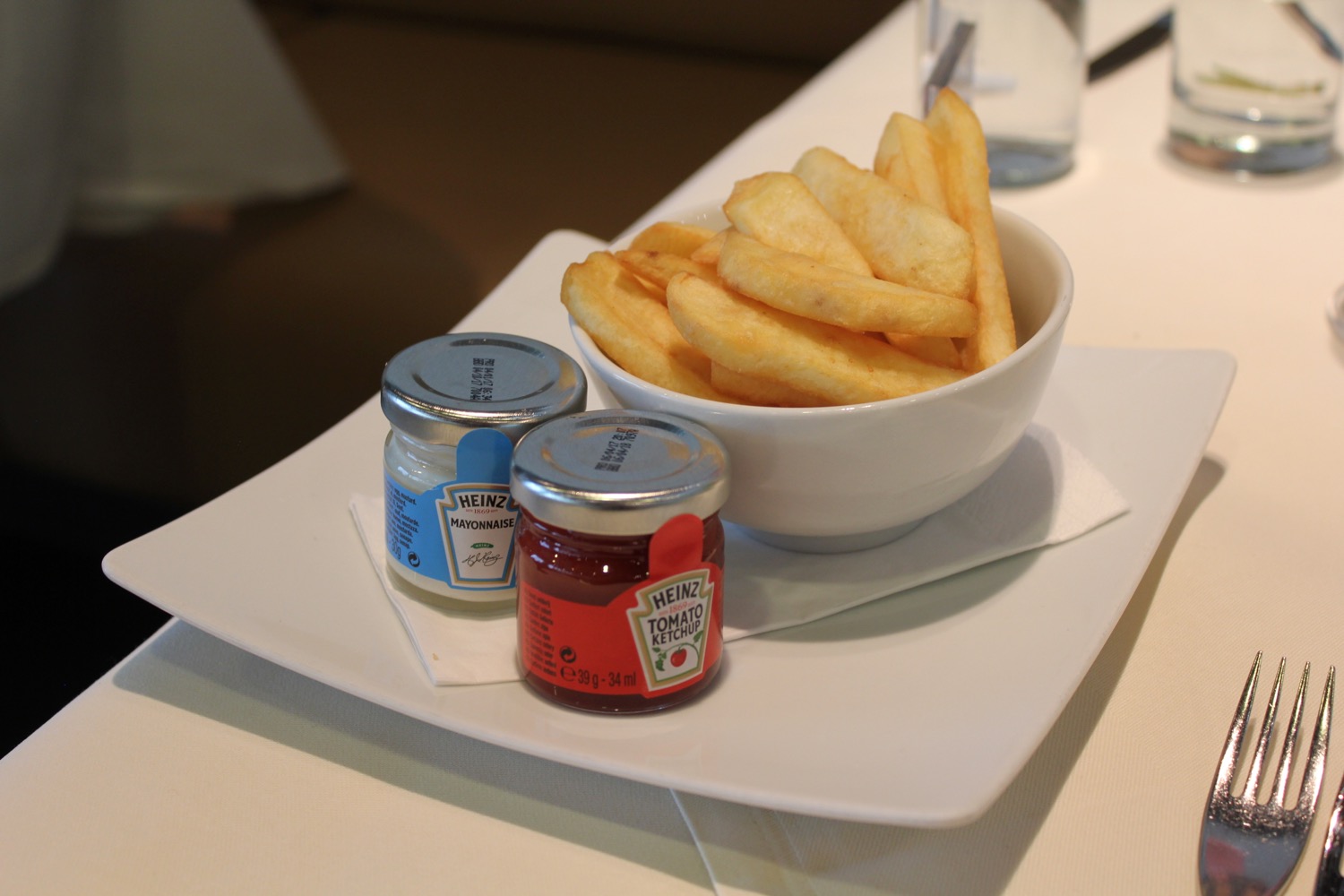 a bowl of french fries and two small condiments on a plate