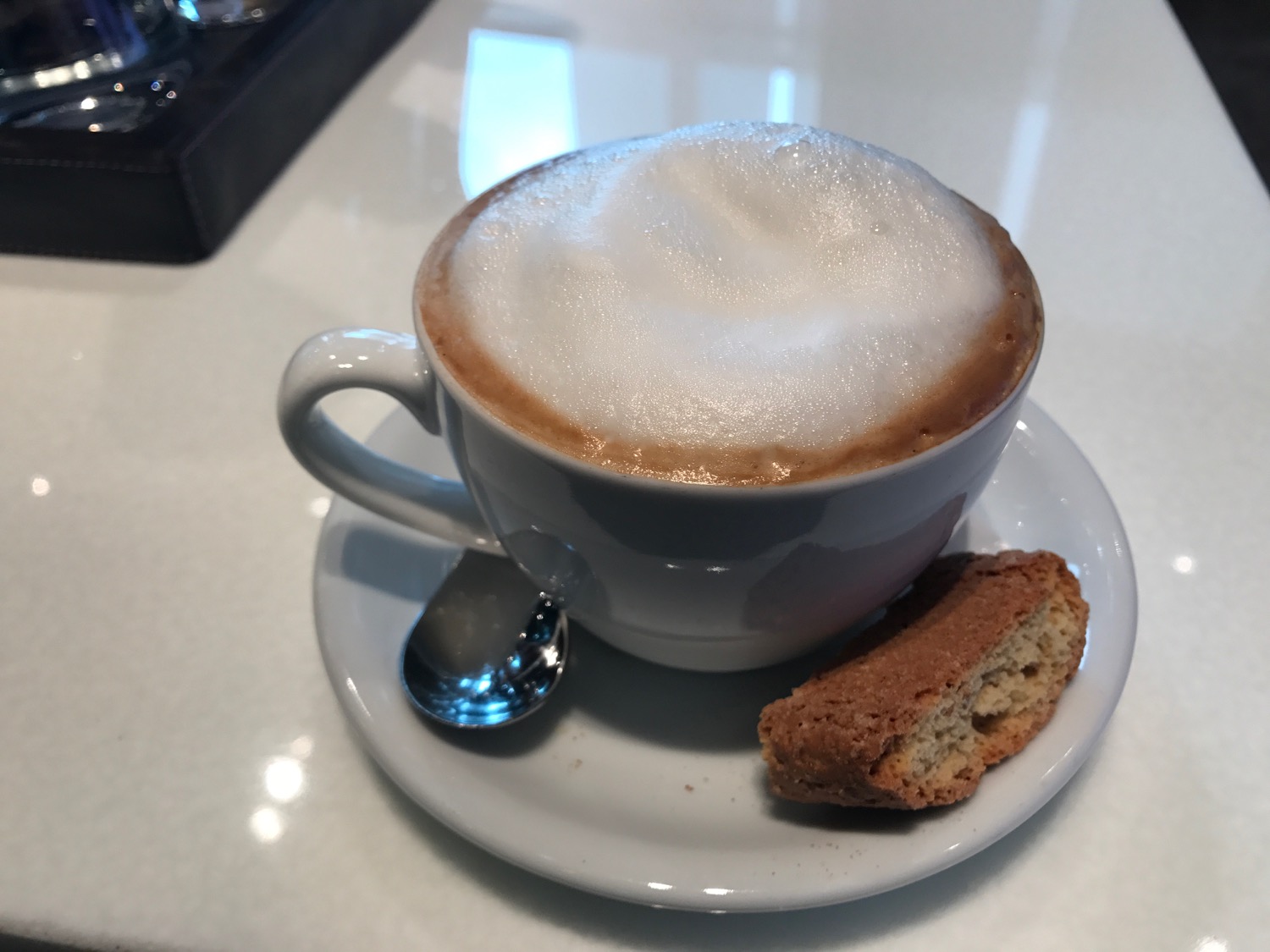 a cup of coffee with a biscotti on a saucer