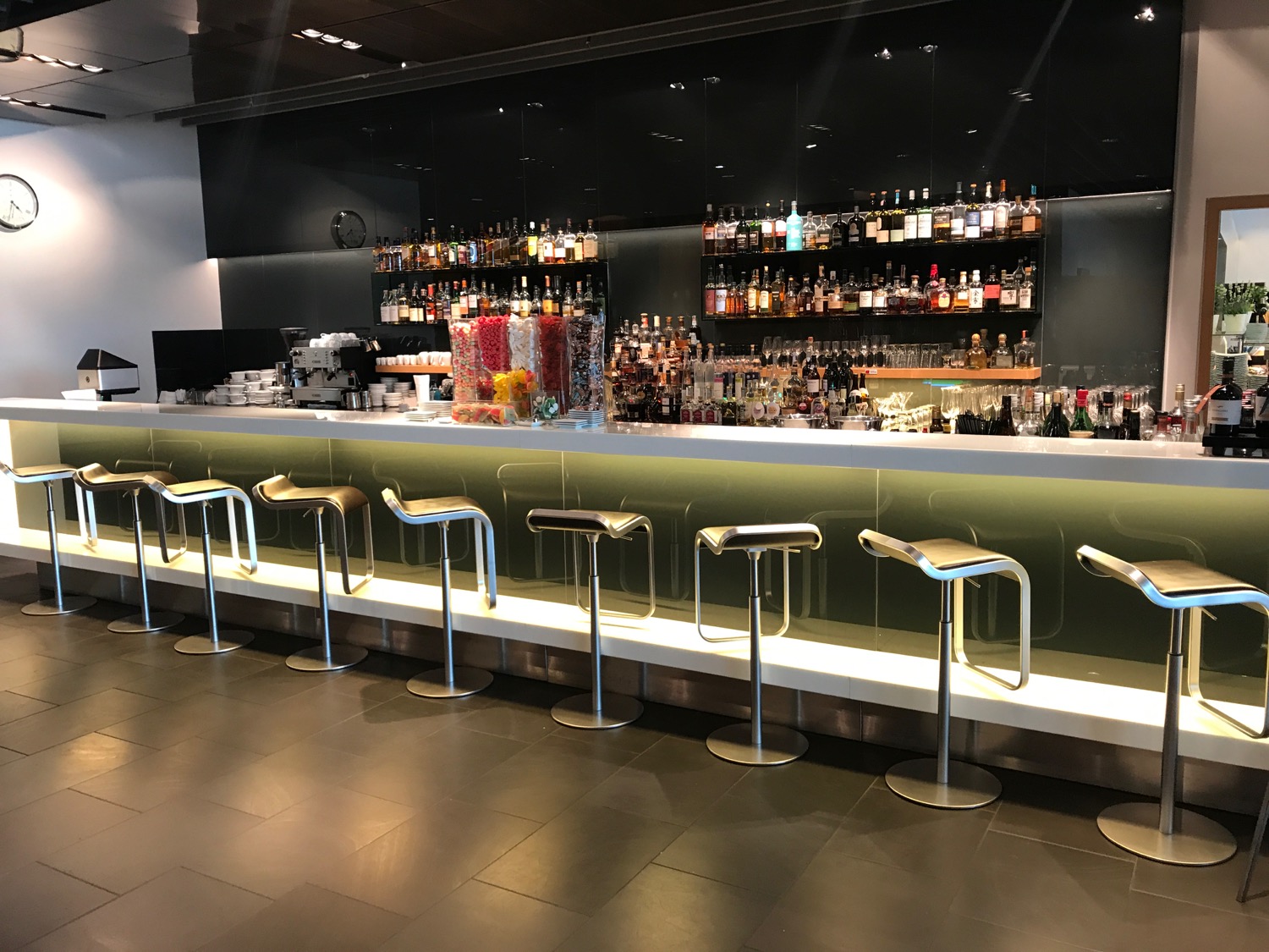 a bar with a row of stools and bottles of liquor