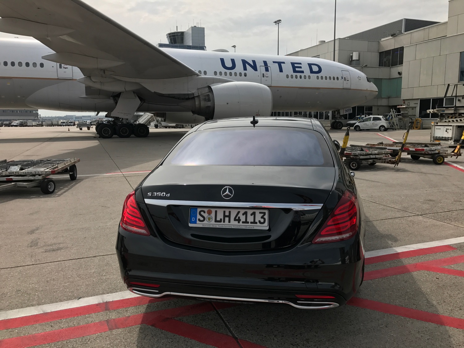 a black car parked on a tarmac next to an airplane