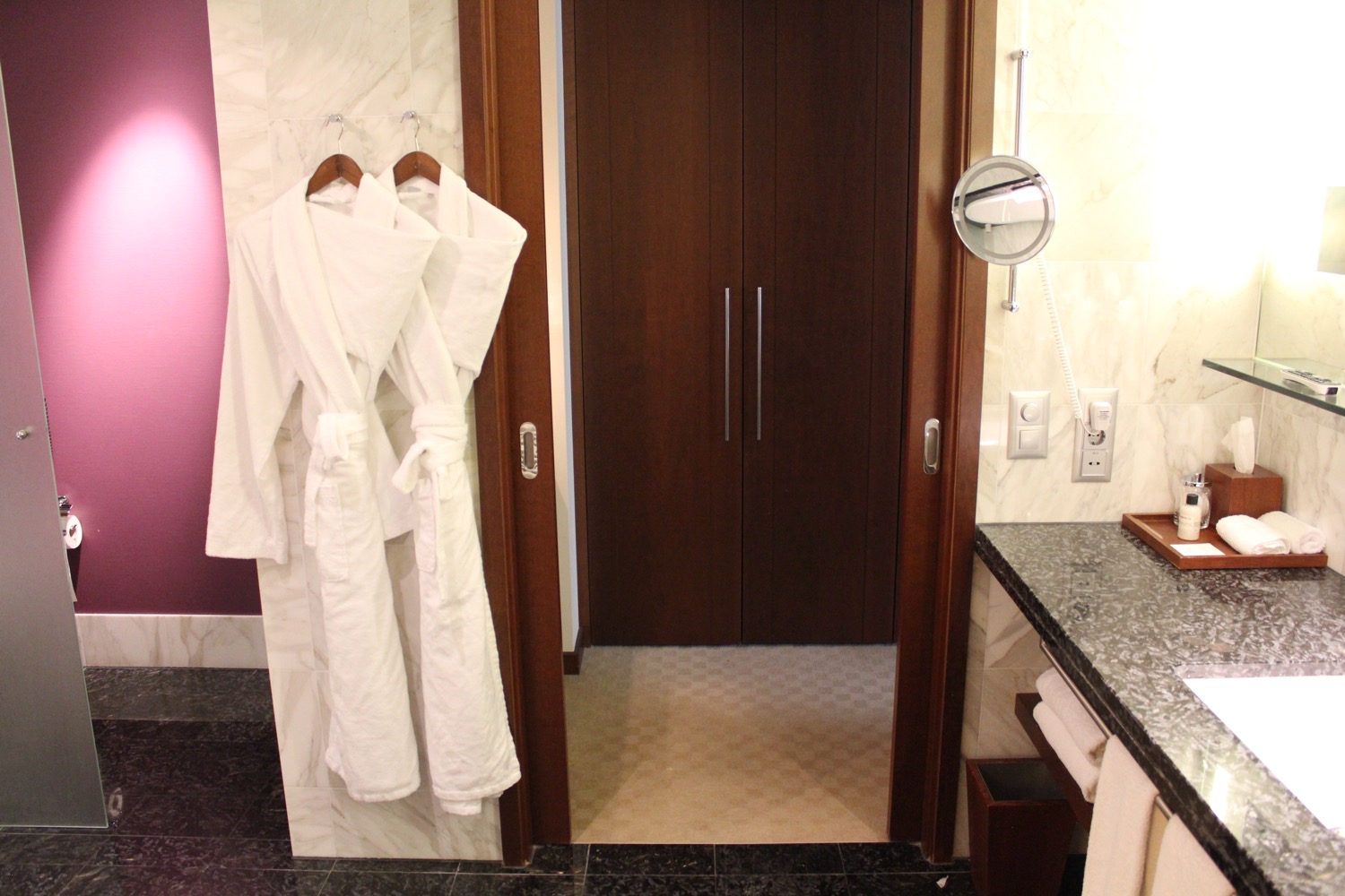 a bathroom with white bathrobes and a mirror