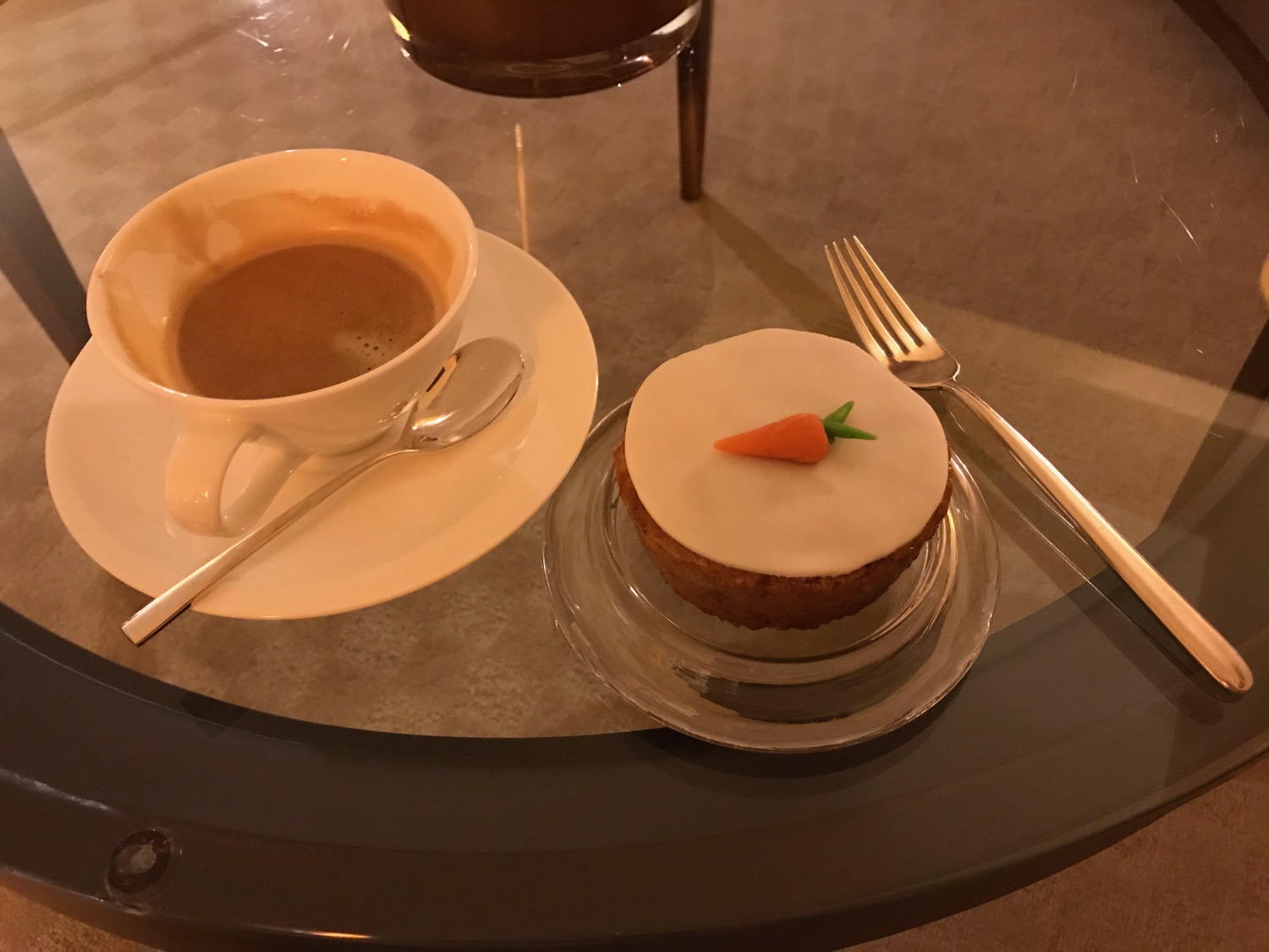 a cupcake and a cup of coffee on a glass table