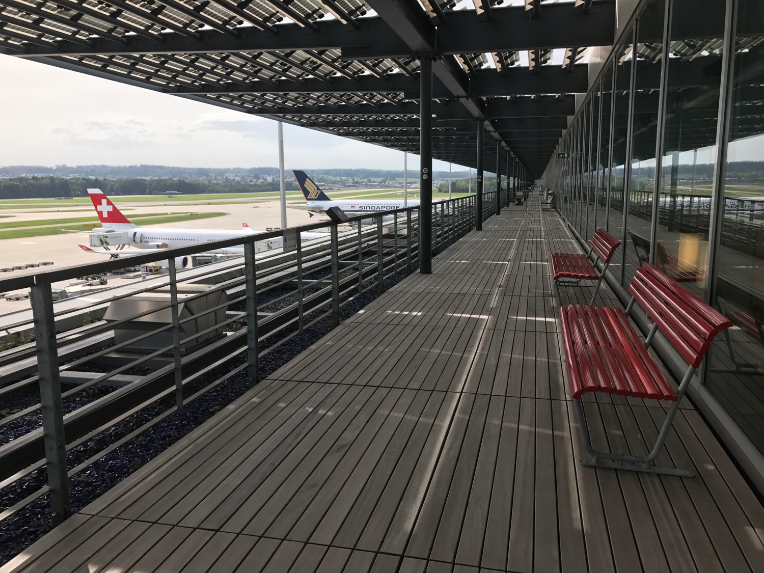 a wooden walkway with benches and a plane in the background