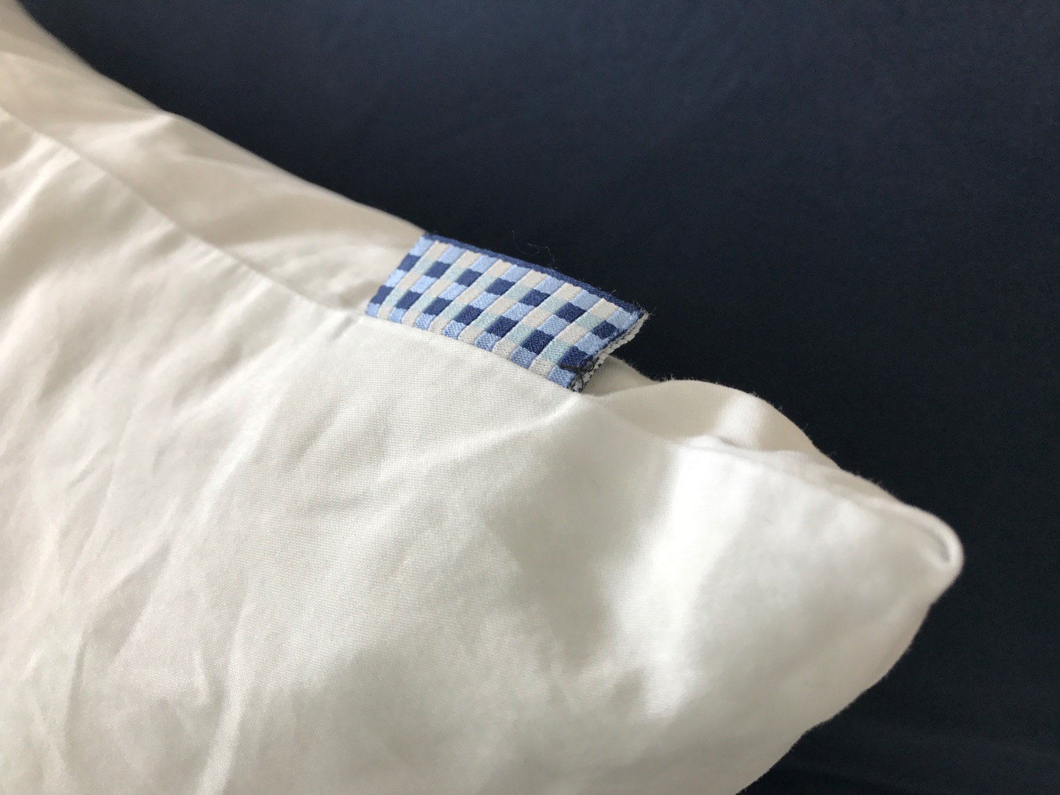 a white pillow with a blue and white checkered fabric tag