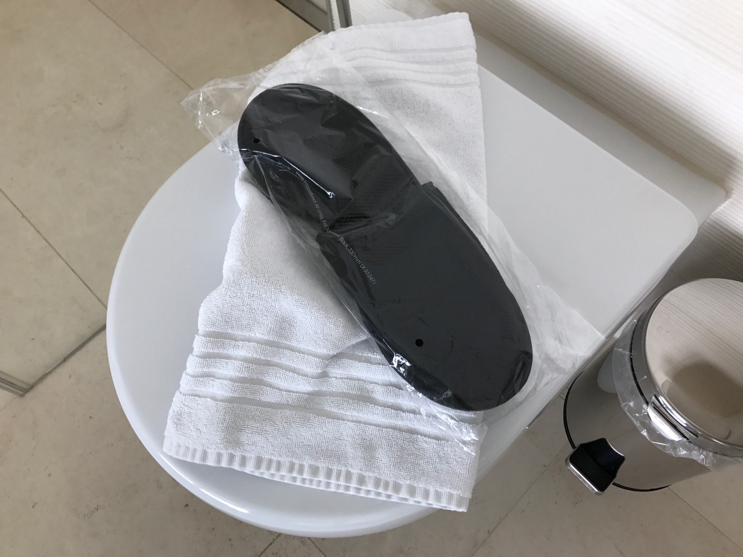 a black shoe in a plastic bag on a white towel