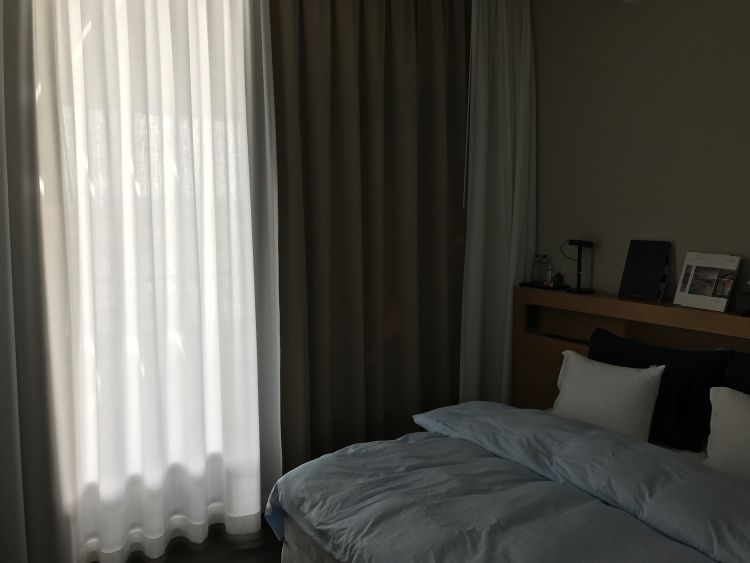 a bed with a white pillow and a white curtain