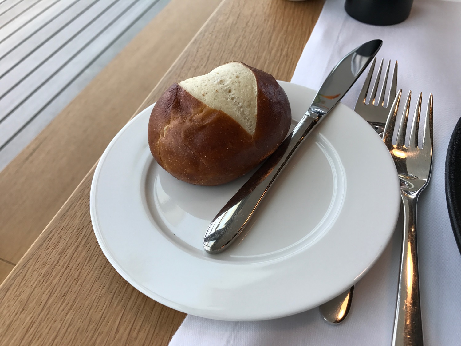 a bread roll on a plate with a knife and fork