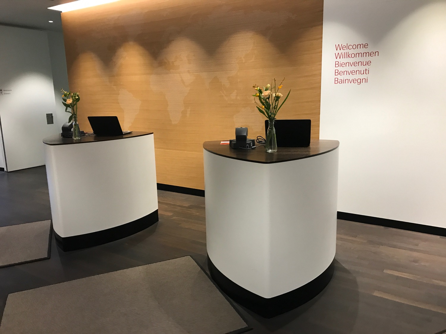 a reception desks with a laptop and flowers in front of a wall