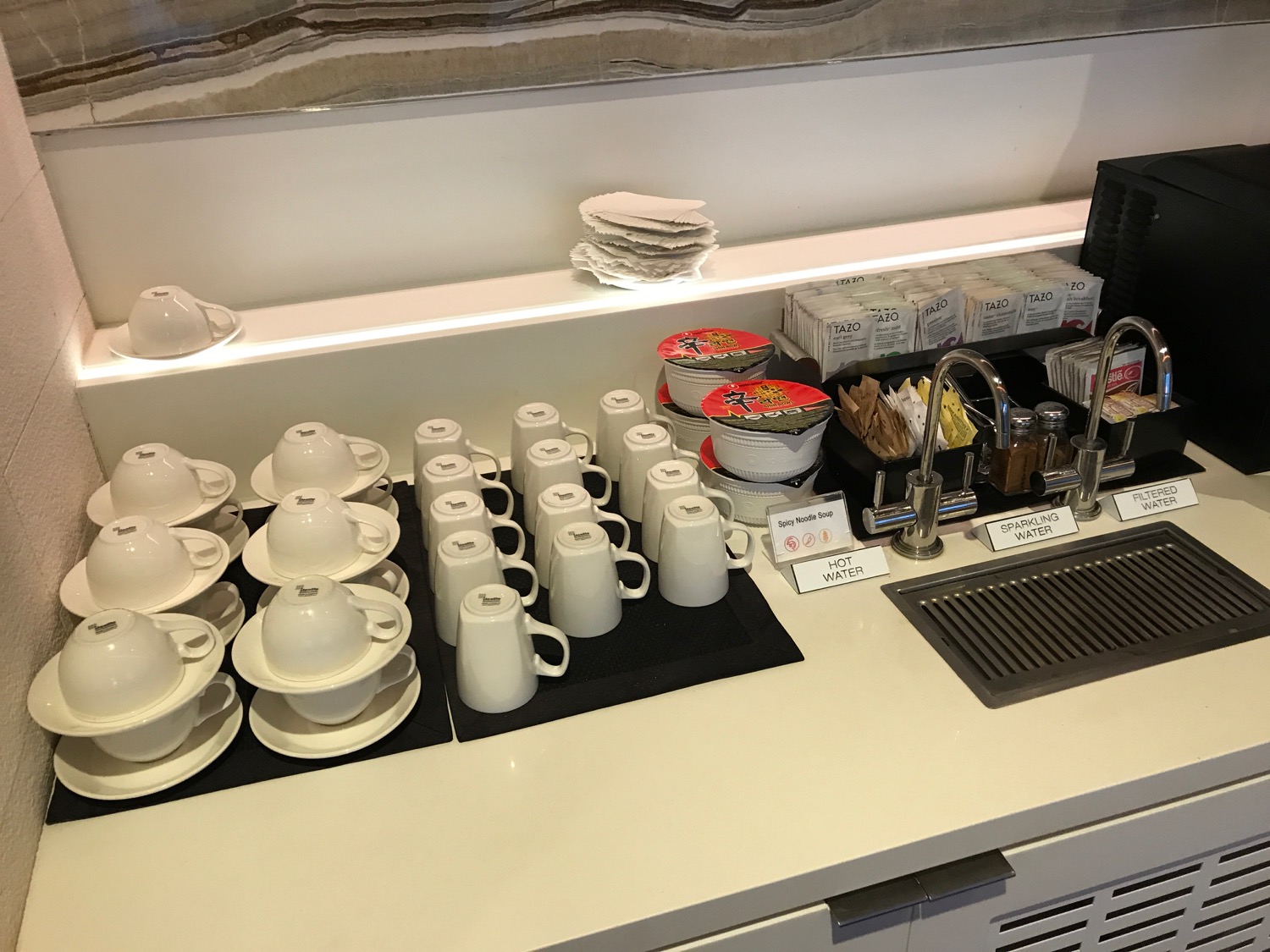 a counter with white cups and saucers