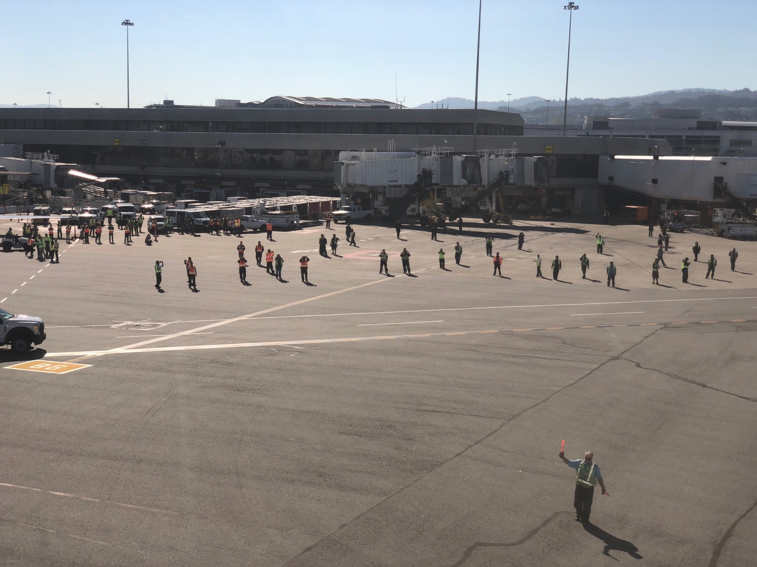 a group of people in orange vests walking on a tarmac