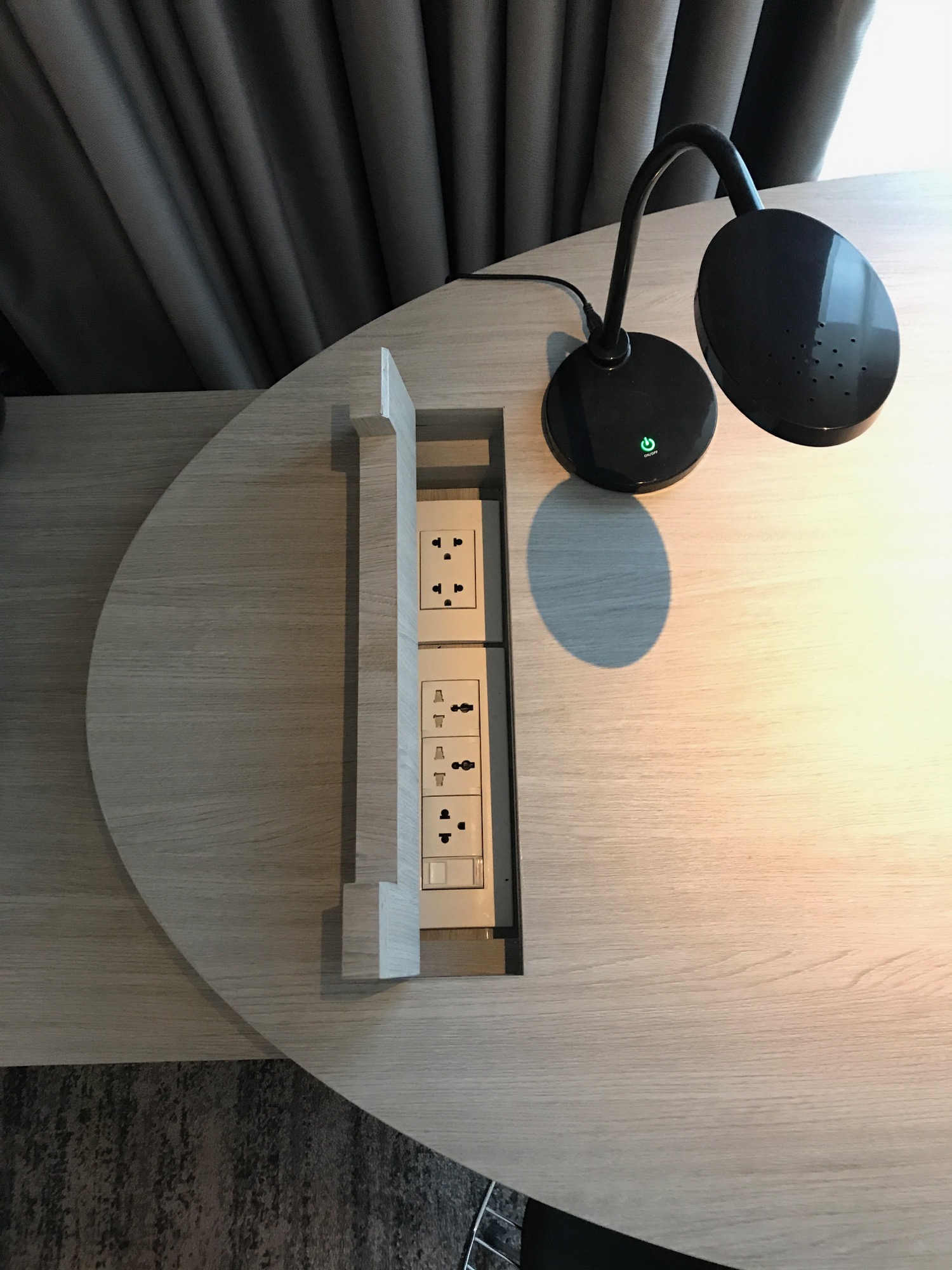 a table with a power strip and a black lamp