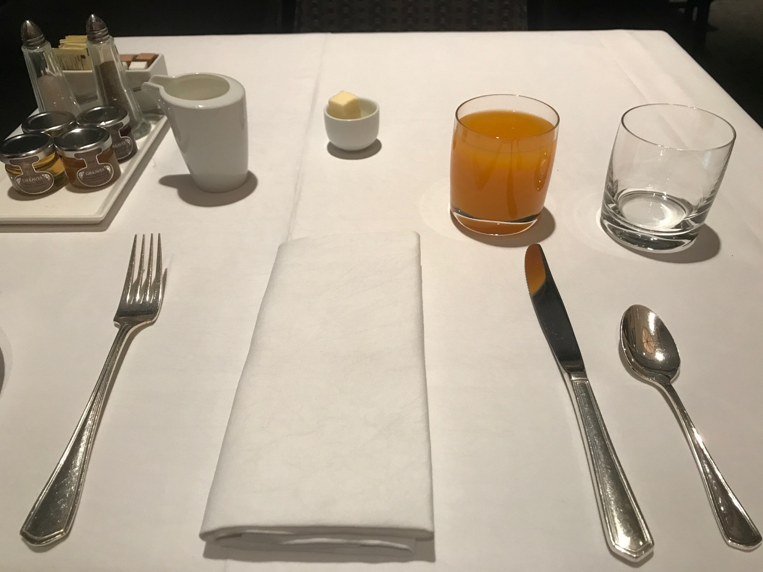 a table with a napkin and glasses of juice and butter