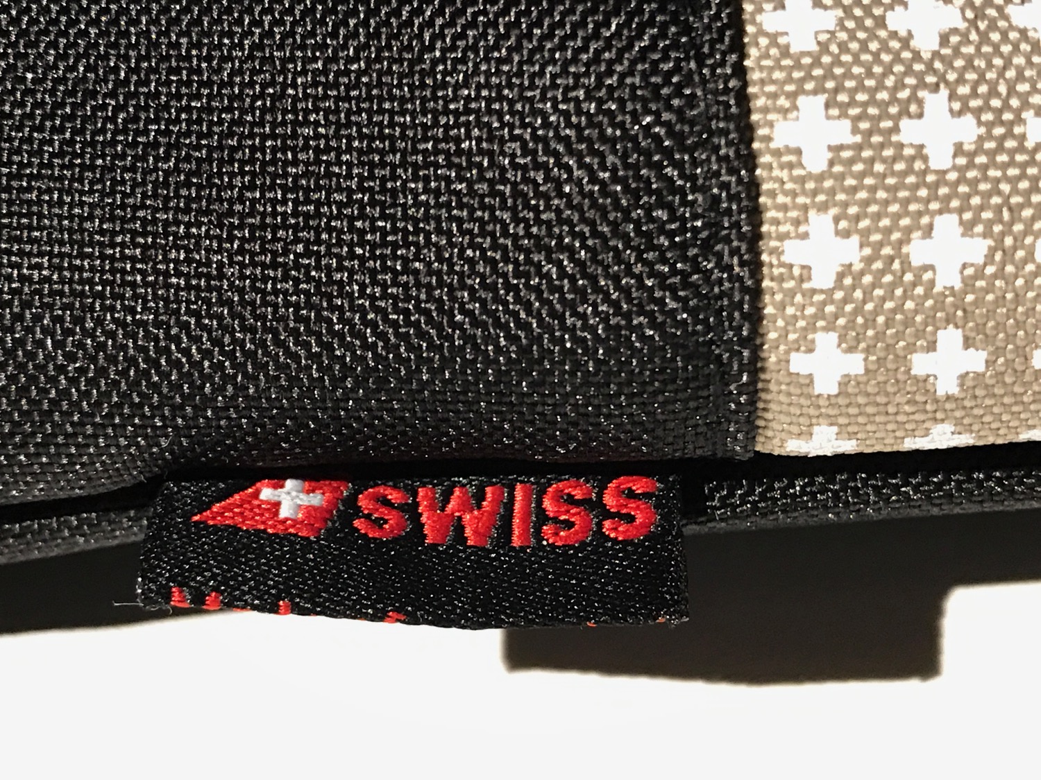 a close up of a black and tan fabric with a red and white logo