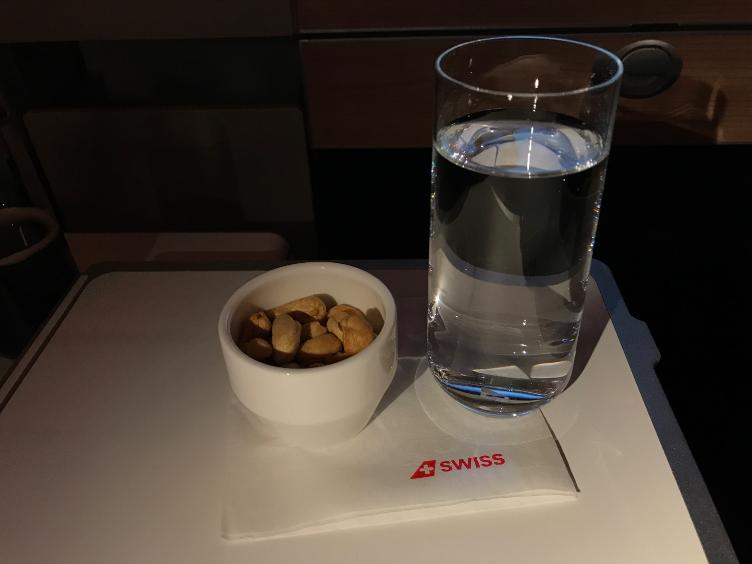 a glass of water and a bowl of peanuts on a table