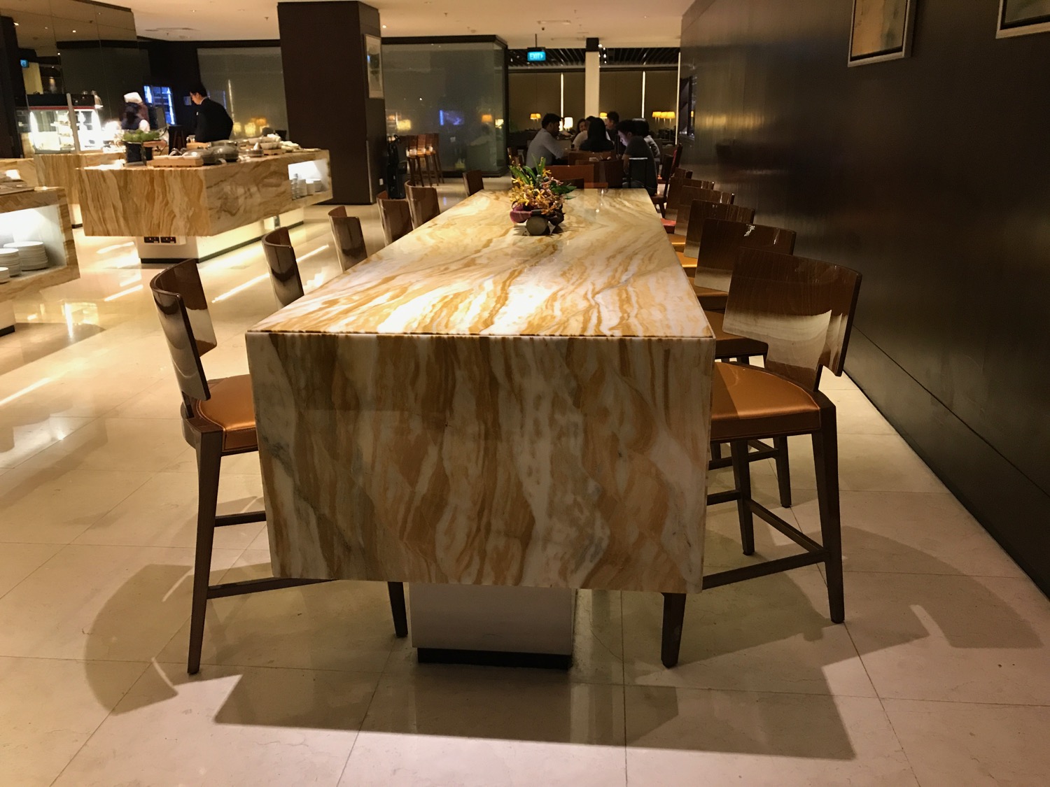a large marble table with chairs in a room with people