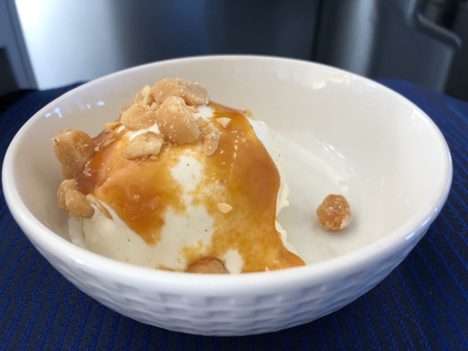 a bowl of ice cream with caramel sauce and nuts