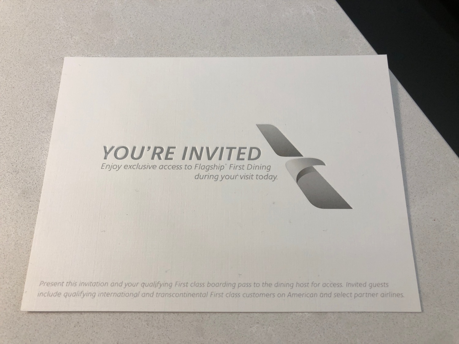 a white rectangular invitation with grey text and black text