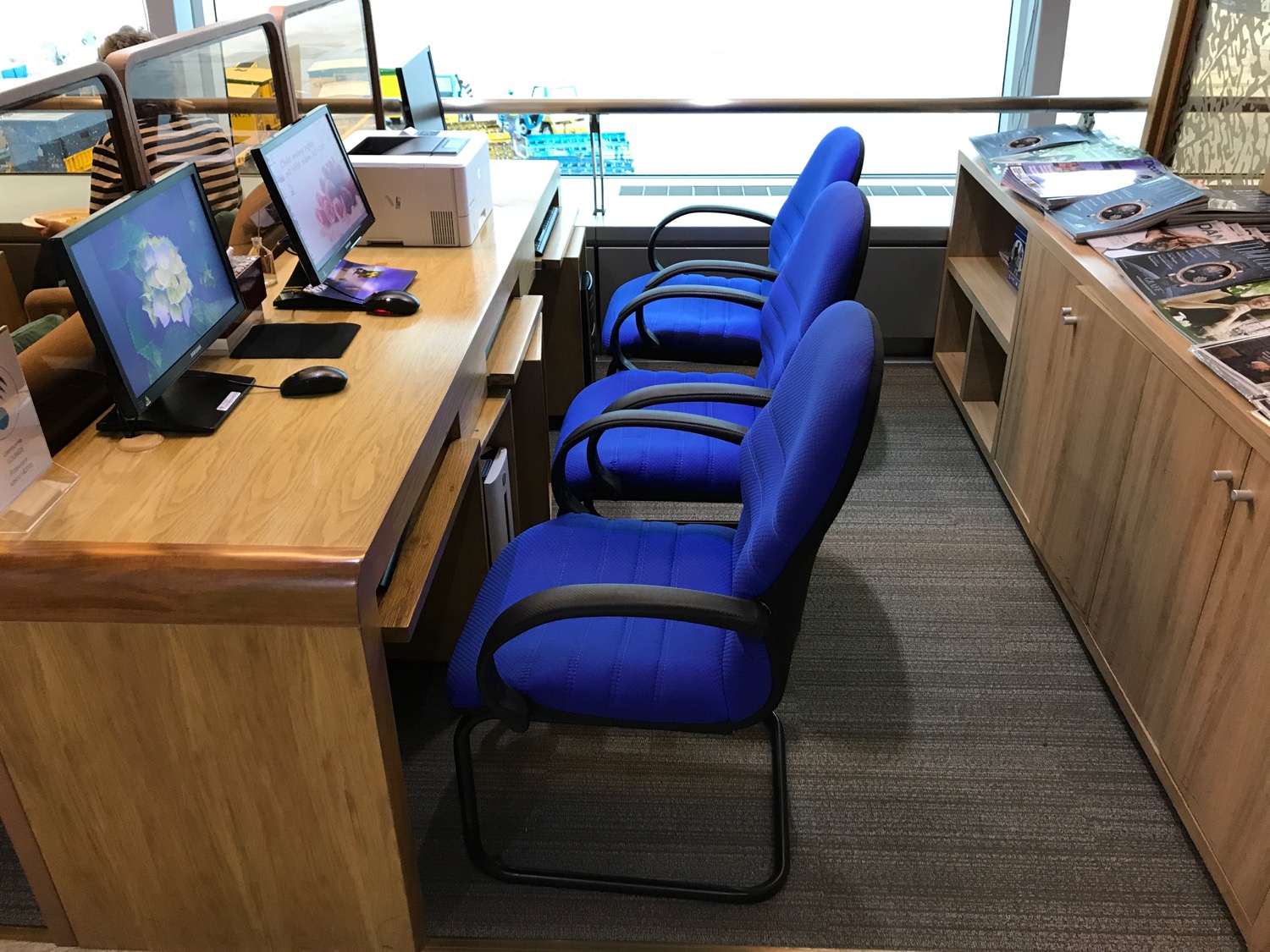 a row of blue chairs and a desk with computers