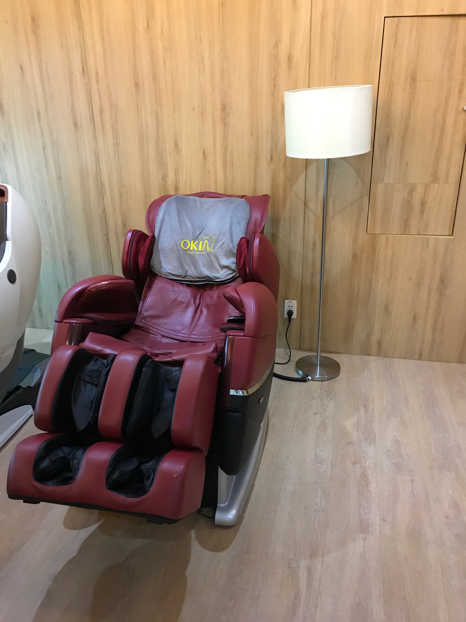 a red massage chair next to a lamp
