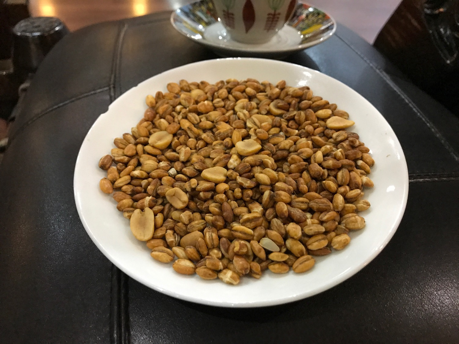 a plate of peanuts on a black surface