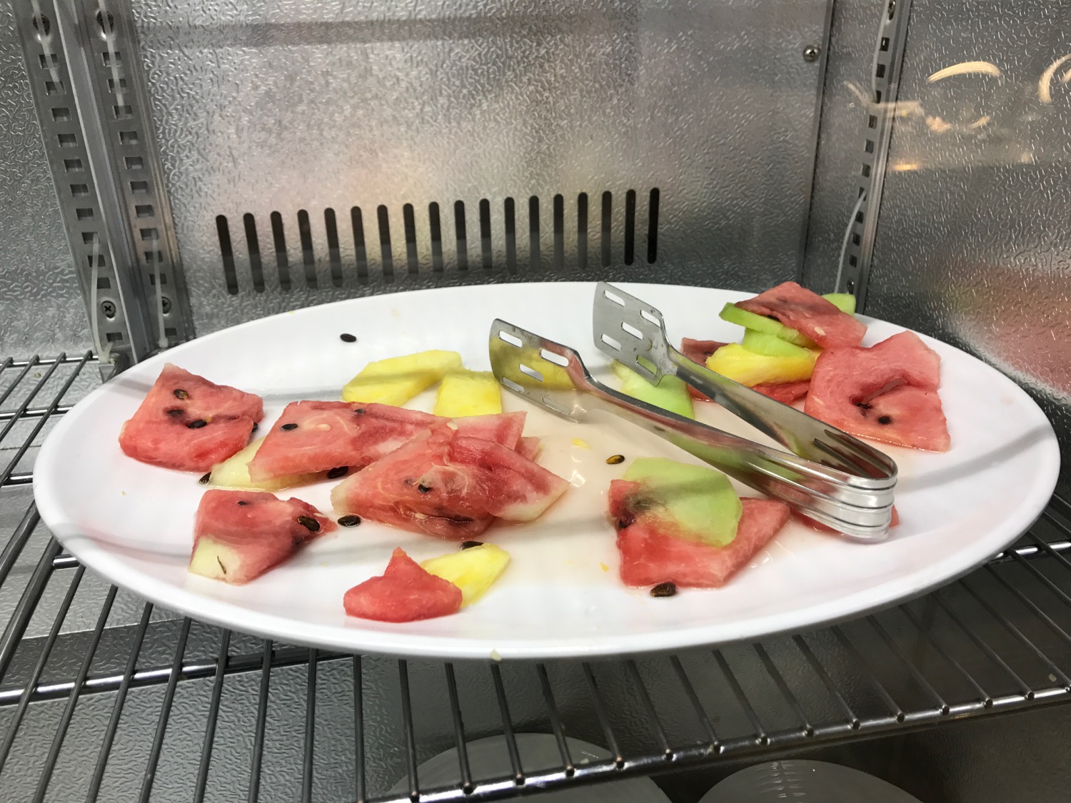 a plate of fruit and tongs