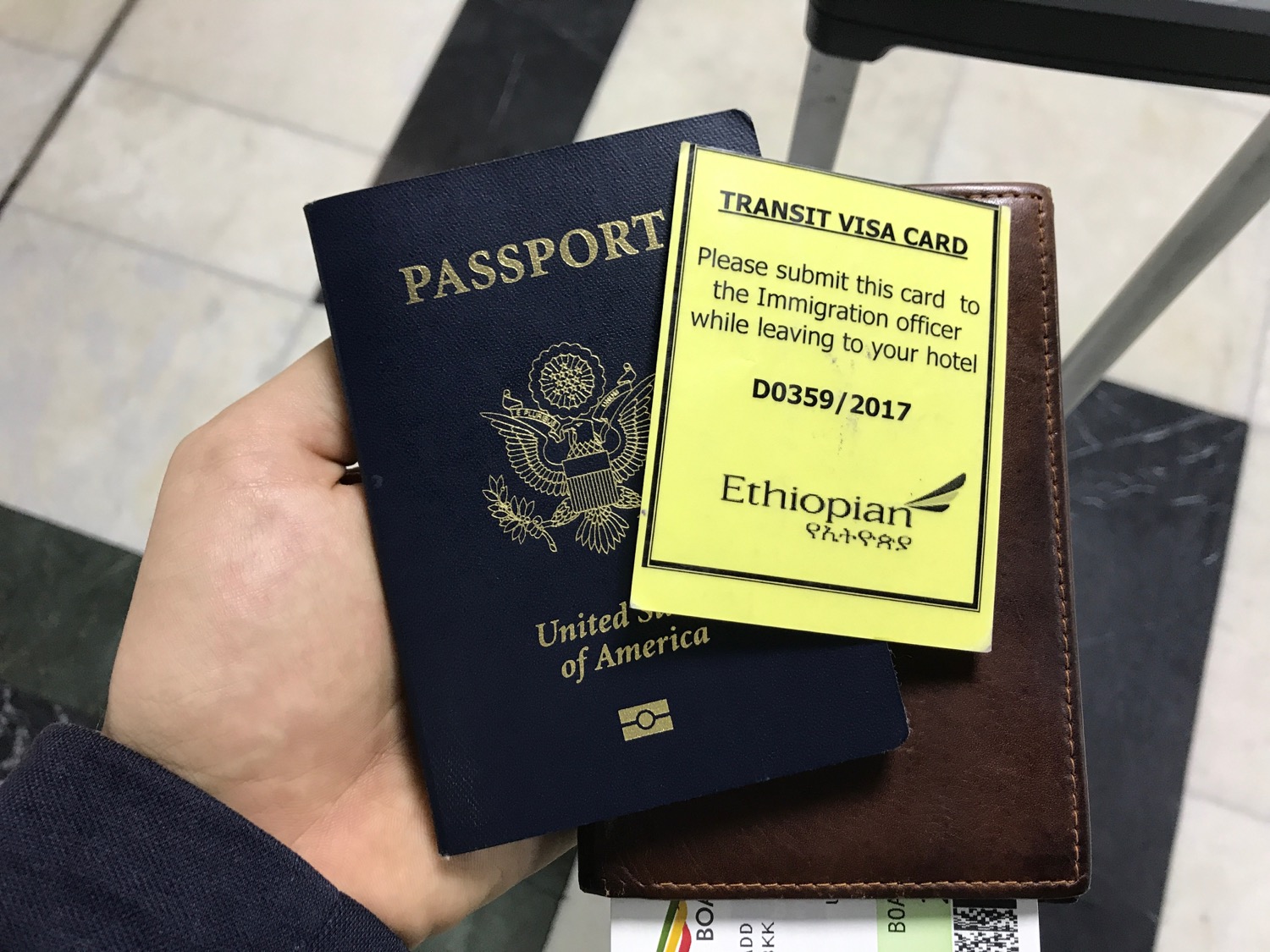 a hand holding a passport and a card