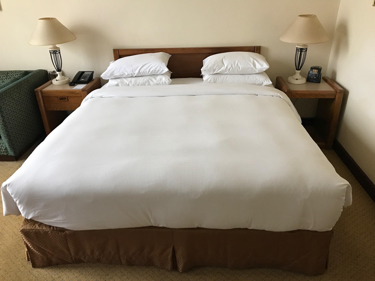 a bed with white sheets and lamps