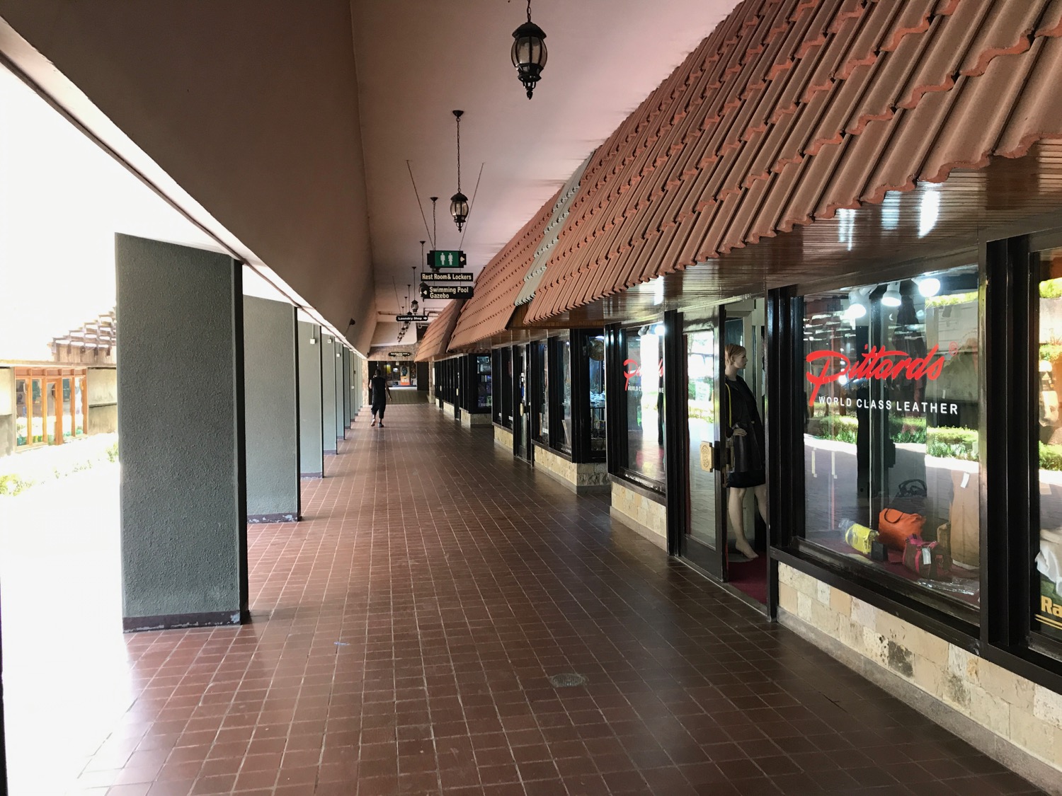 a walkway with storefronts and people walking