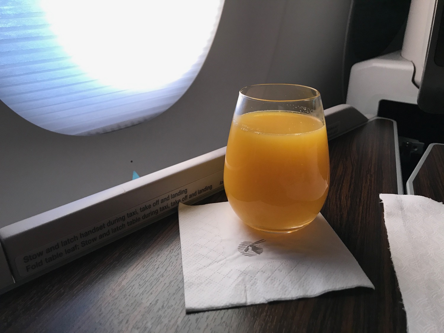 a glass of orange juice on a napkin on a table