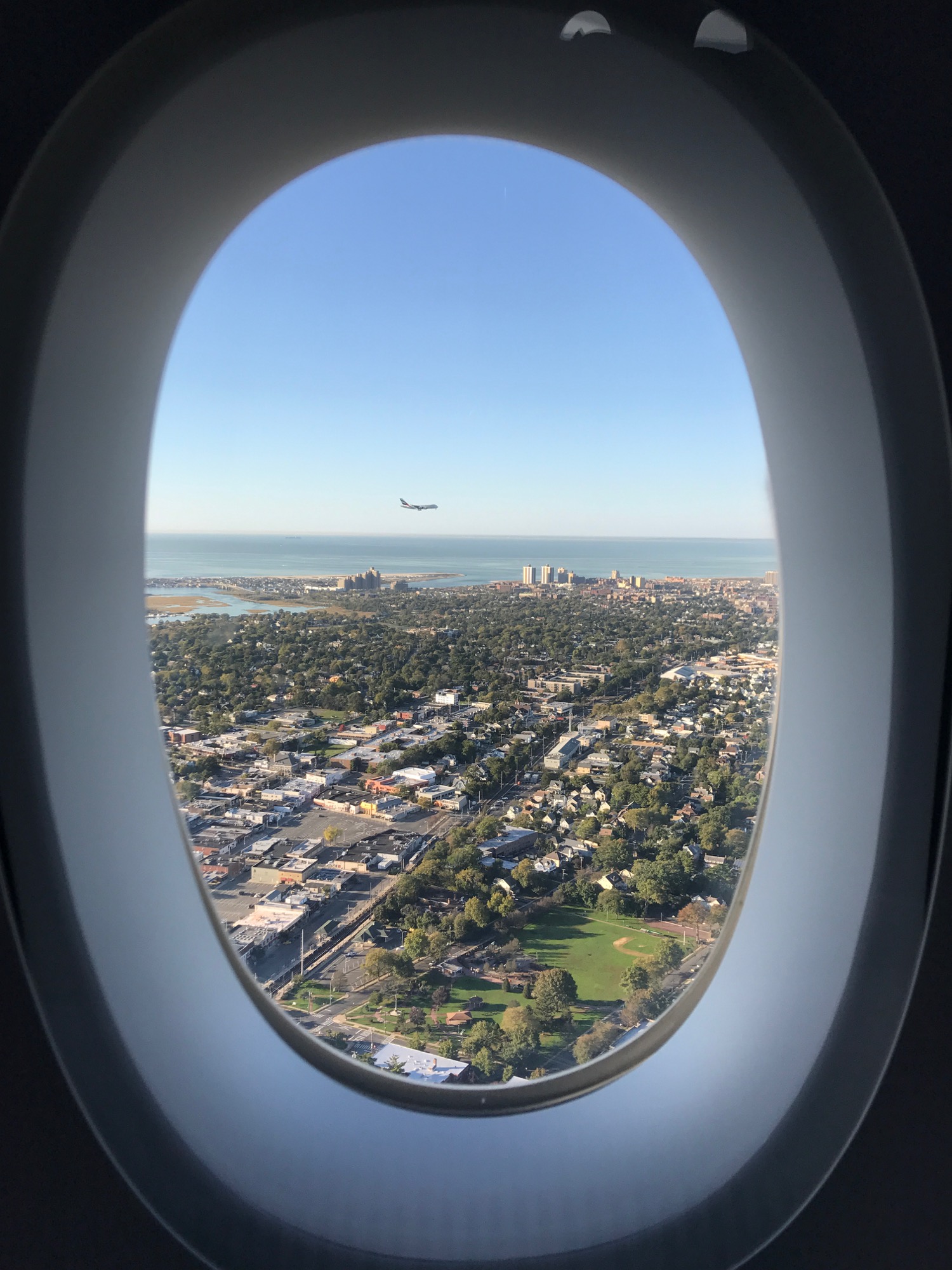 an airplane window with a city and water in the background