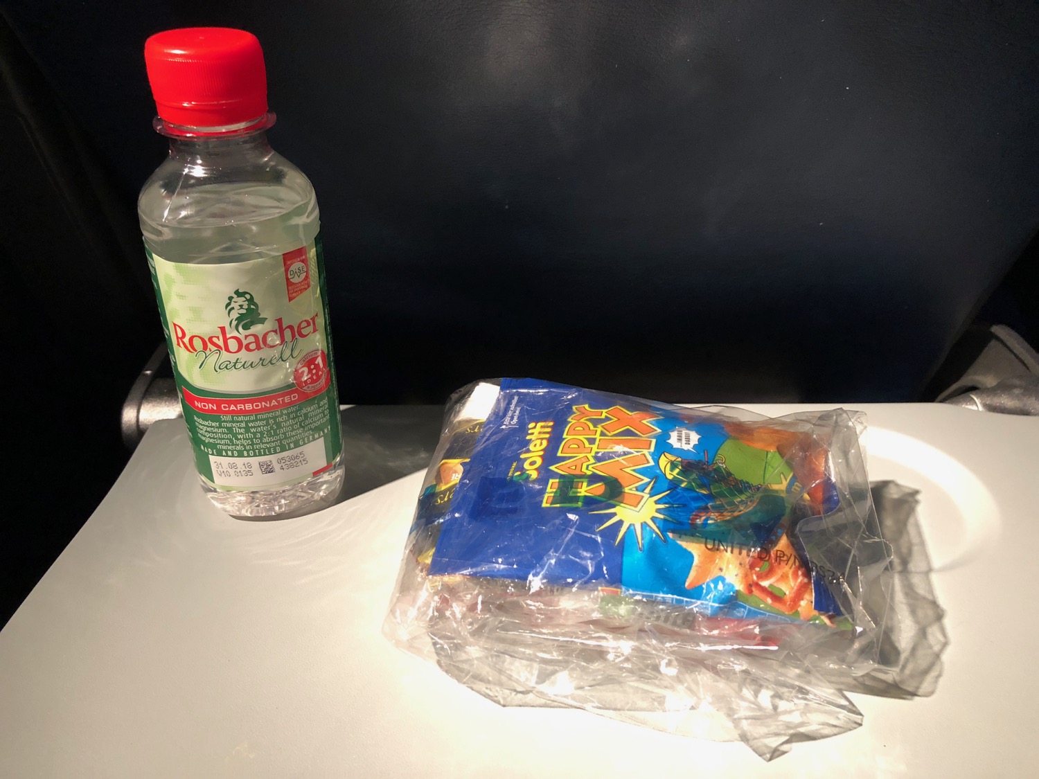 a plastic bag of food next to a bottle of water