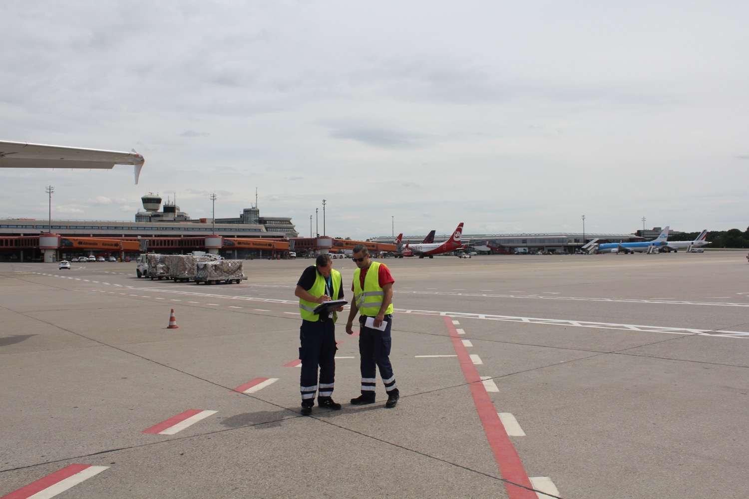 two men in reflective vests standing on a runway