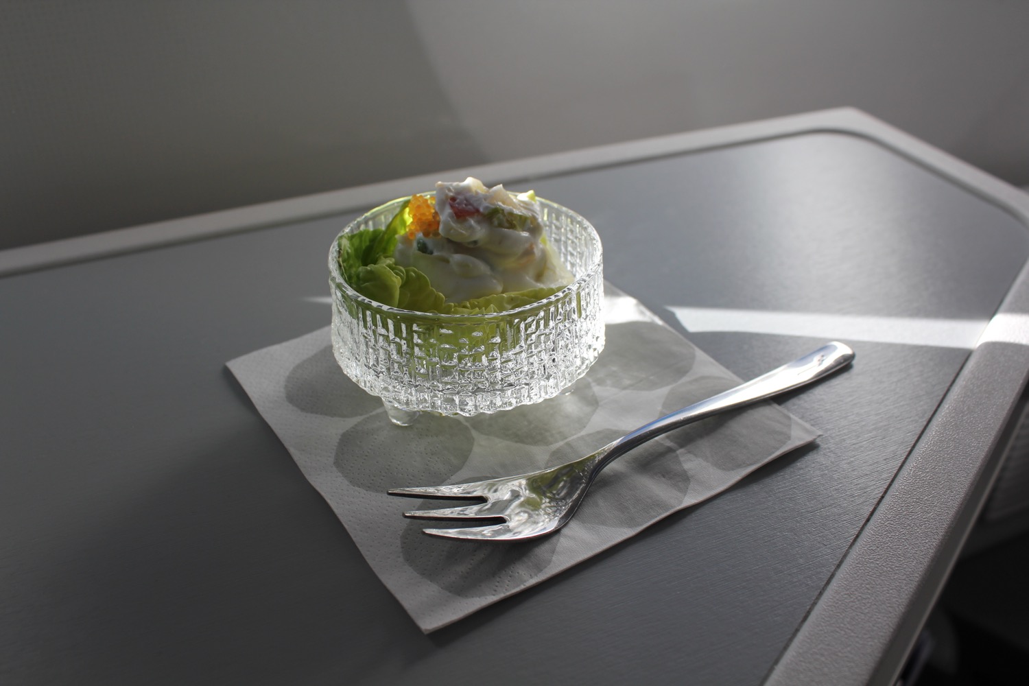 a glass bowl with food in it and a fork on a napkin
