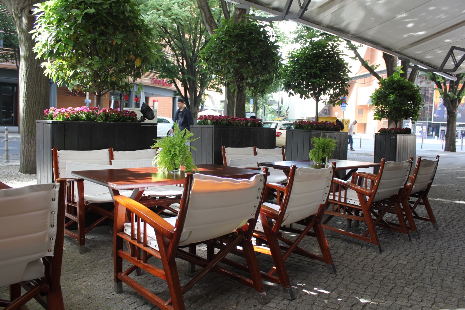 a table and chairs outside with trees and plants