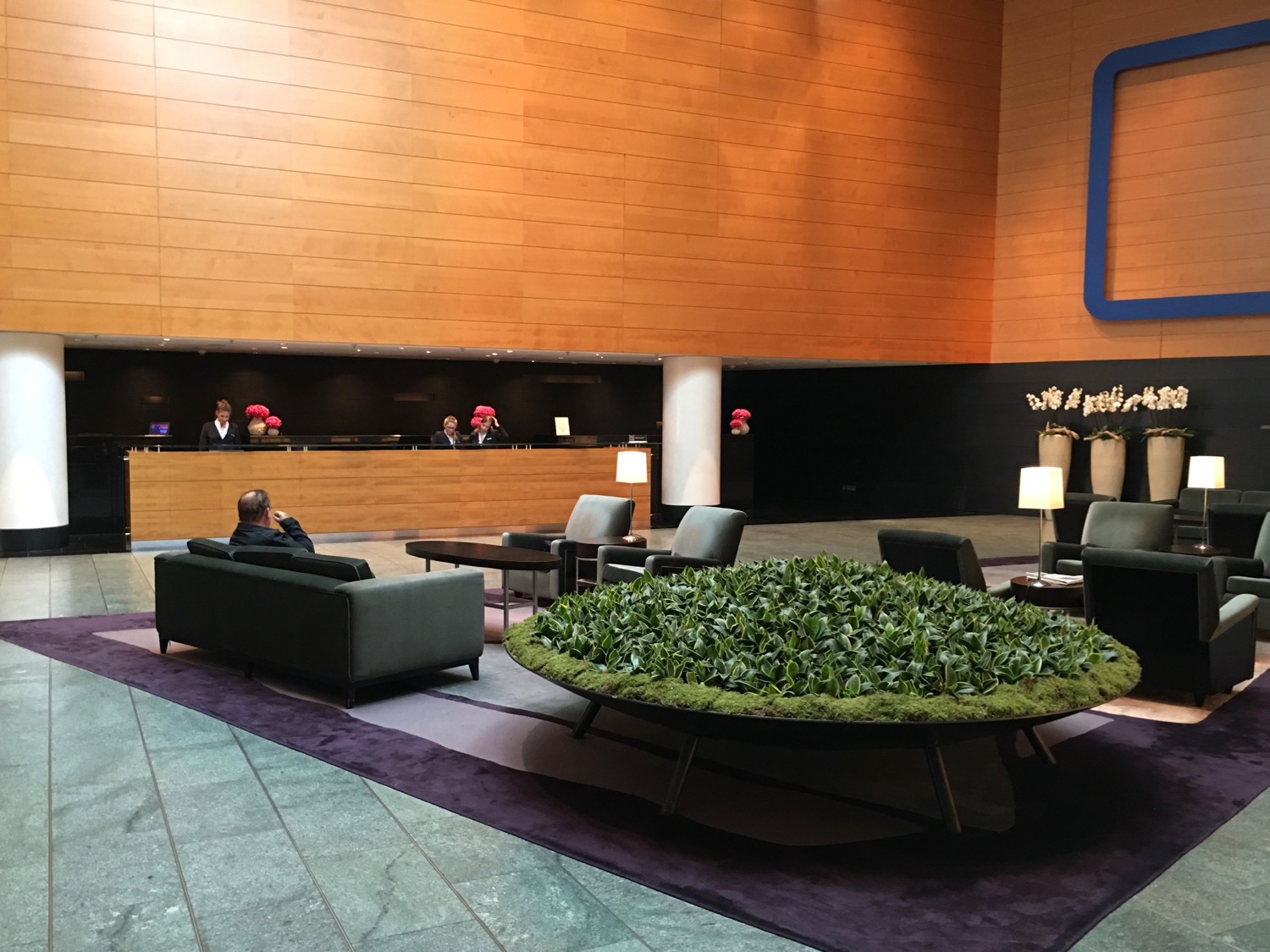 a lobby with a reception desk and a man sitting on a couch
