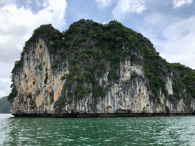 a large rock formation in the water with Ha Long Bay in the background