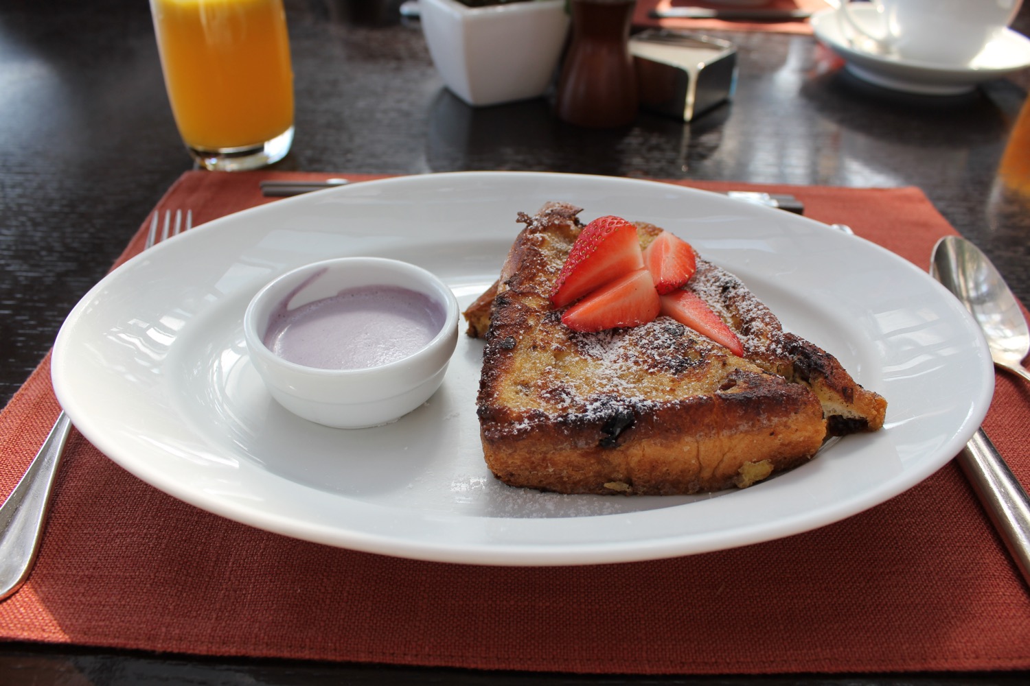a plate of french toast with strawberries and sauce