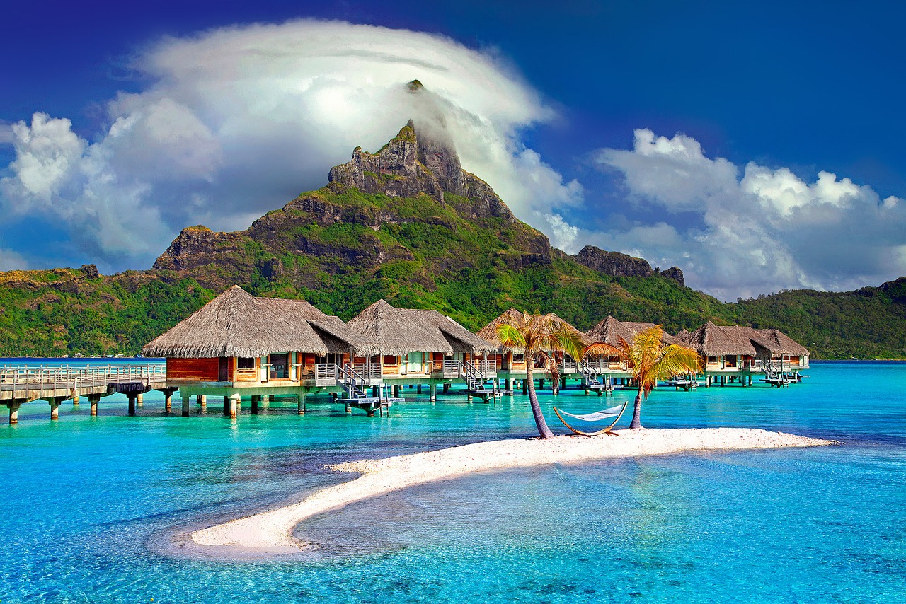 a group of houses on water with a hammock in front of Bora Bora
