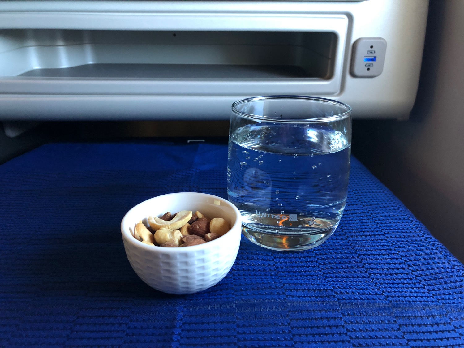 a bowl of nuts and a glass of water next to a microwave