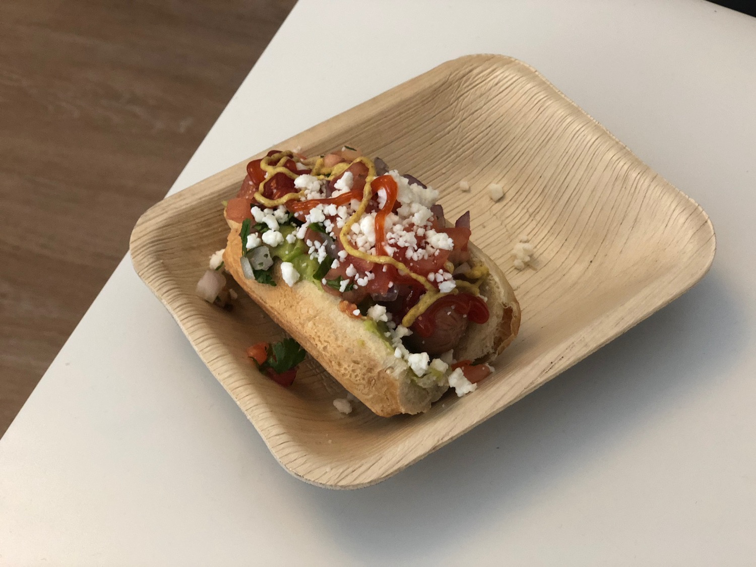 a hot dog with toppings on a wooden plate