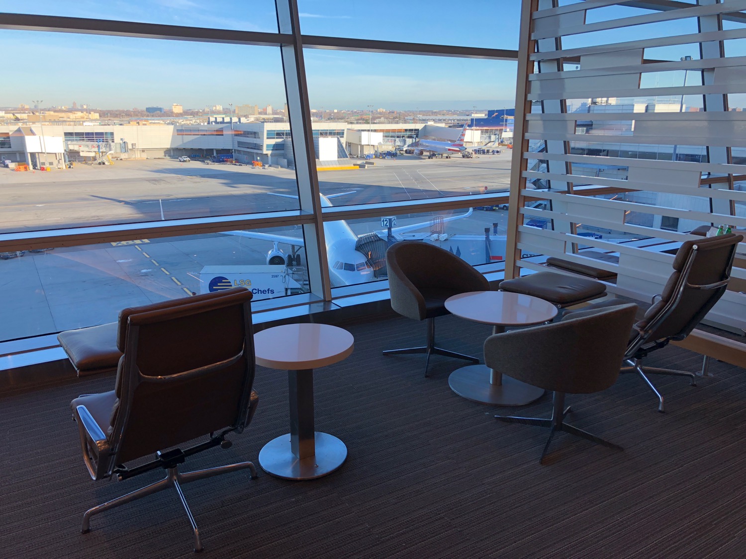 a room with chairs and tables and a window with a view of an airport