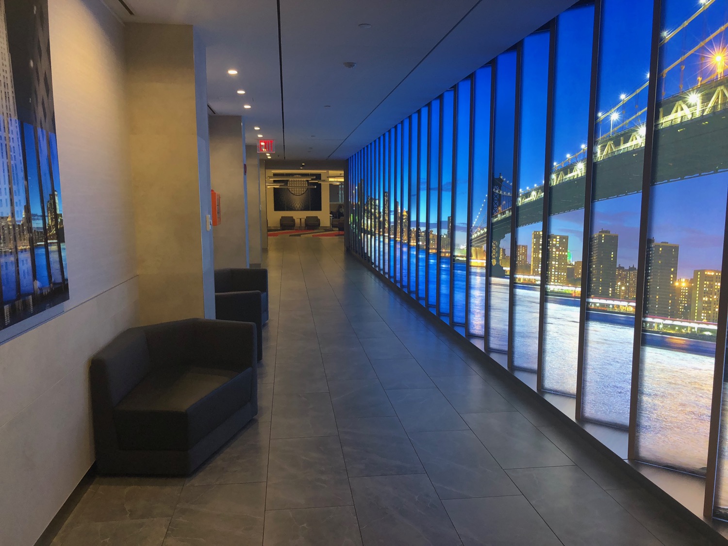 a long hallway with a view of a city and a bridge through windows