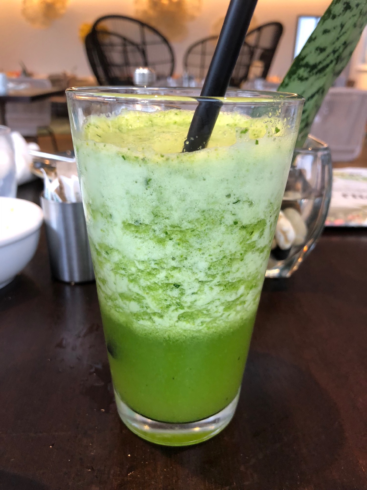 a glass with a green drink and a black straw