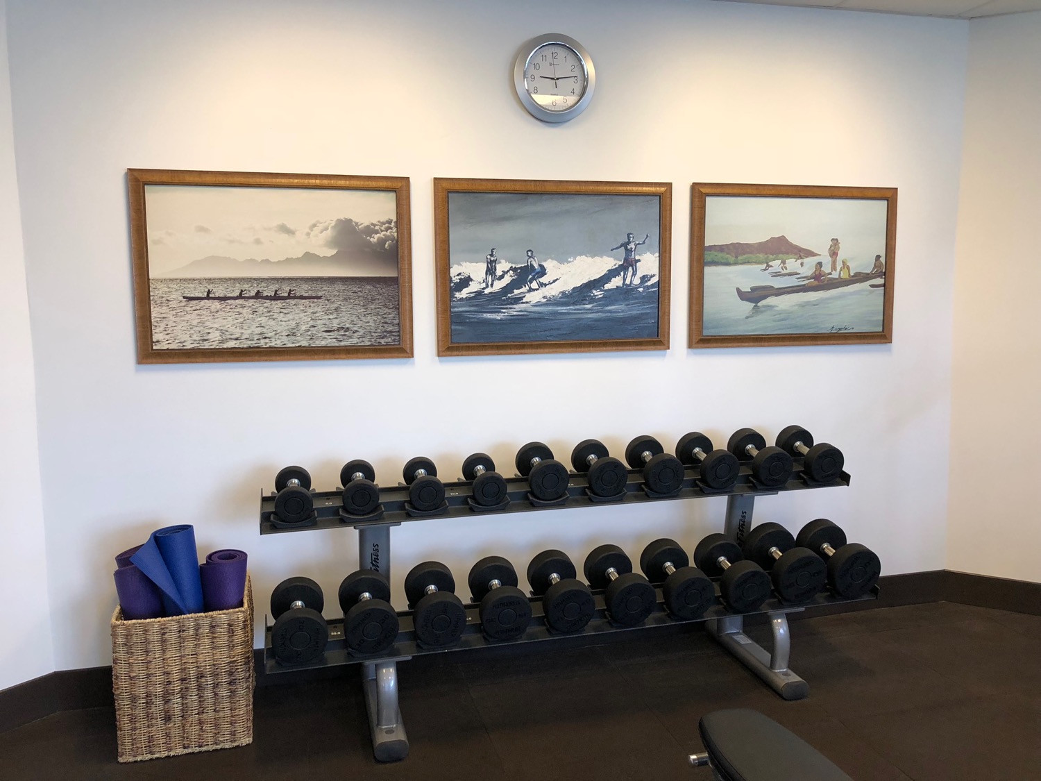 a room with a wall of art and a rack of dumbbells