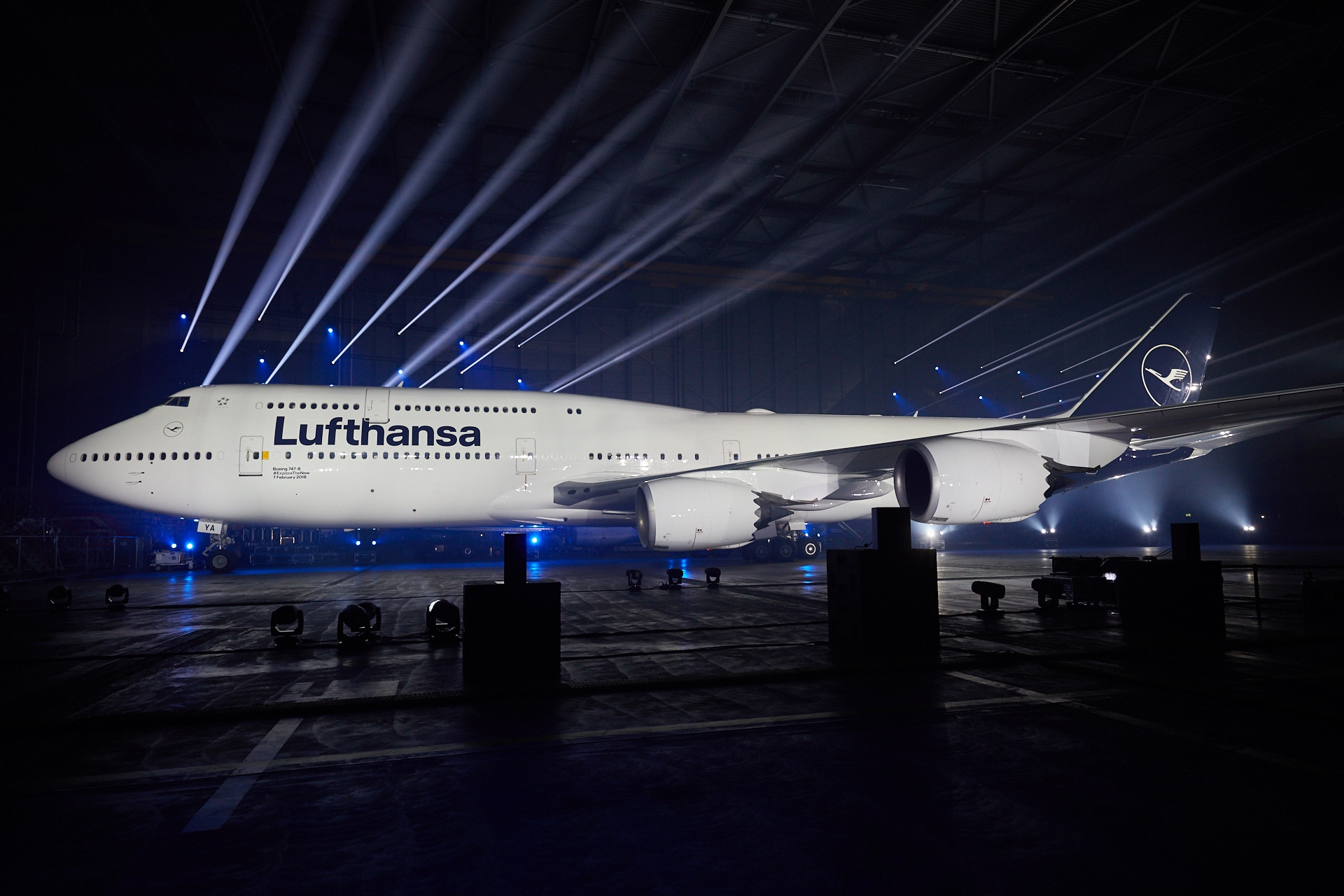 a large white airplane in a hangar with lights