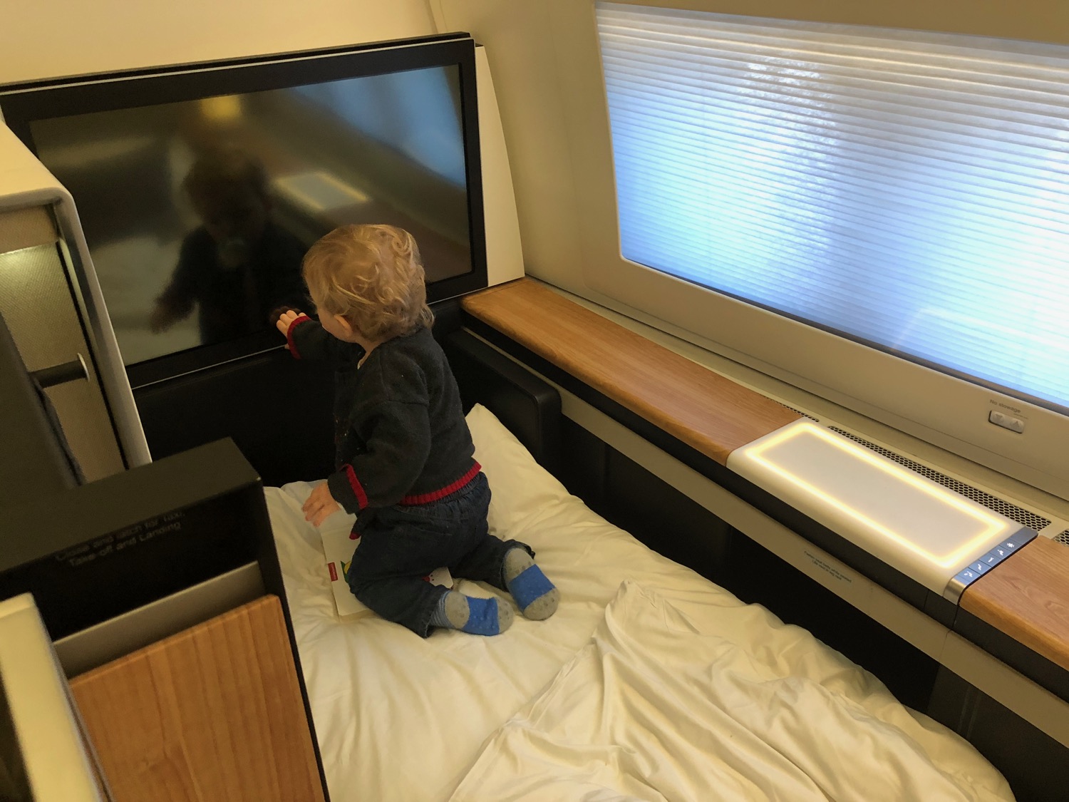a child sitting on a bed watching a television