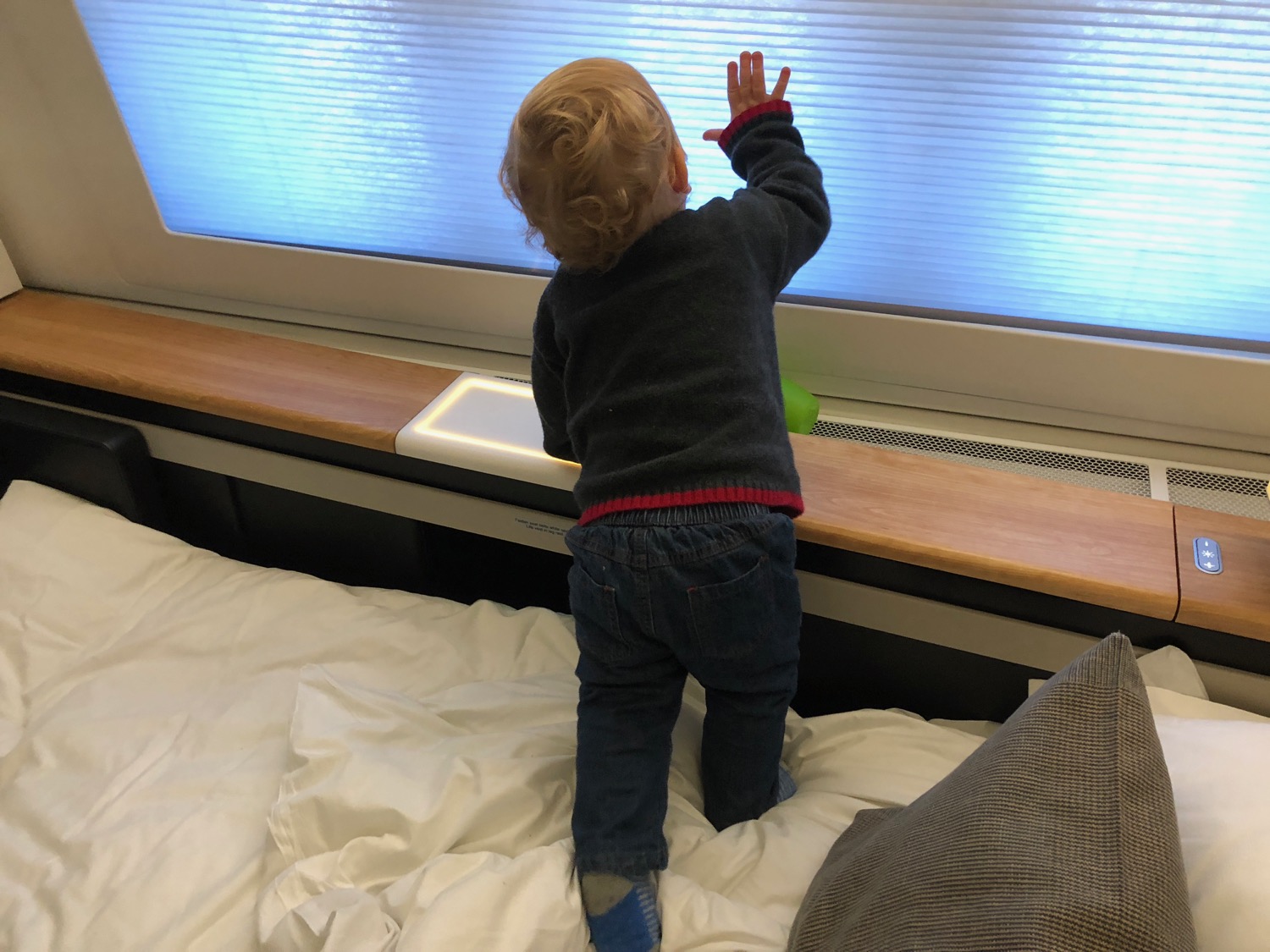 a child standing on a bed looking at a window