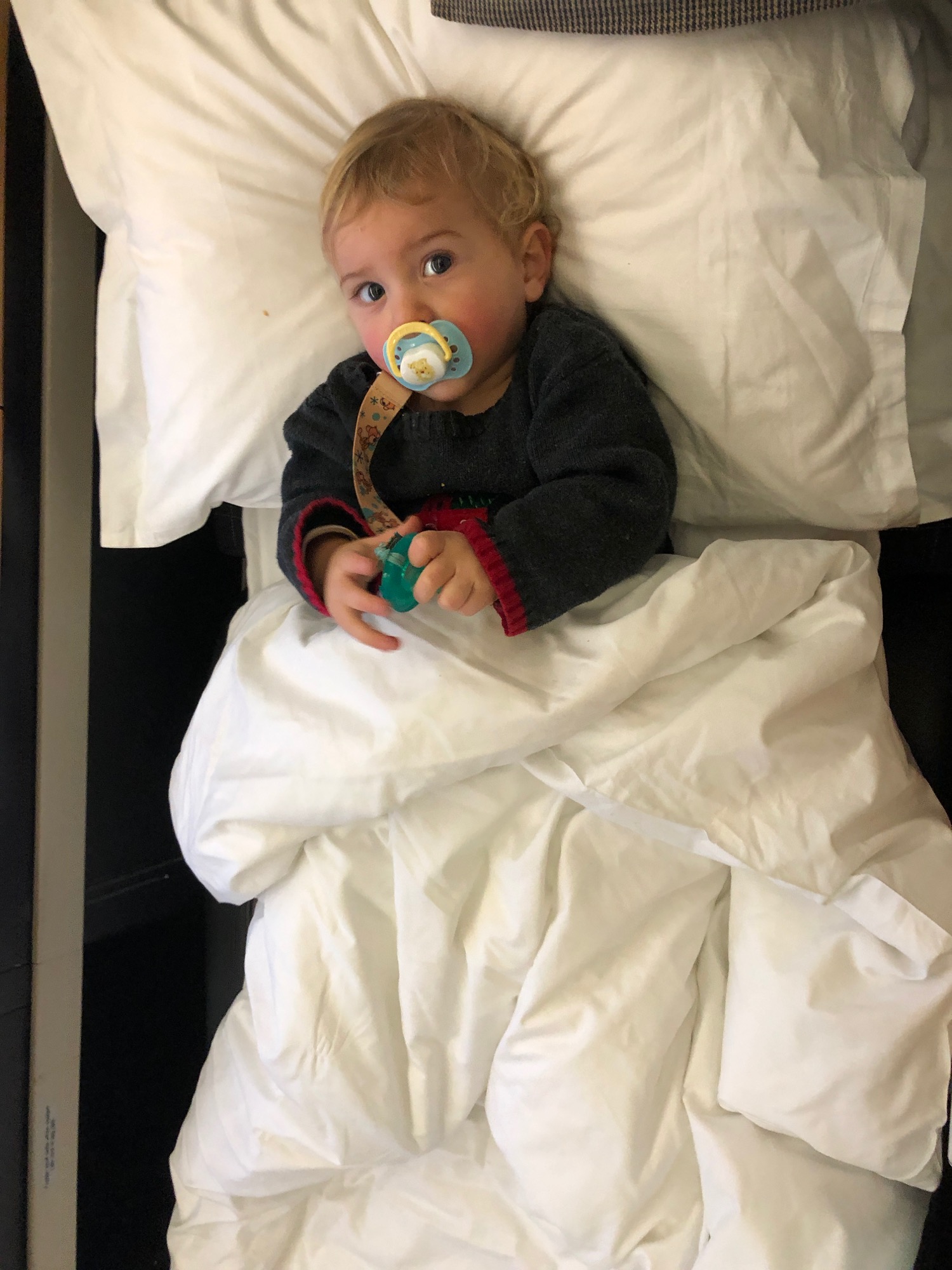 a baby lying in a bed with a pacifier